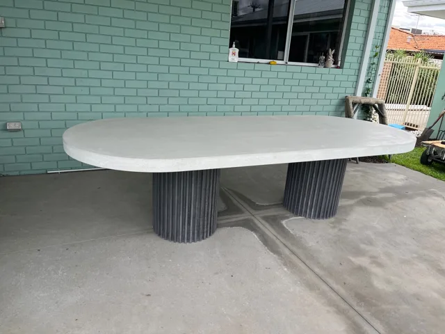 Oval dining table: An oval top paired with two dark fluted bases.