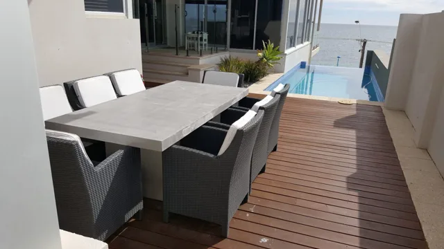 Poolside dining table: A long rectangular table in a coastal outdoor setting.