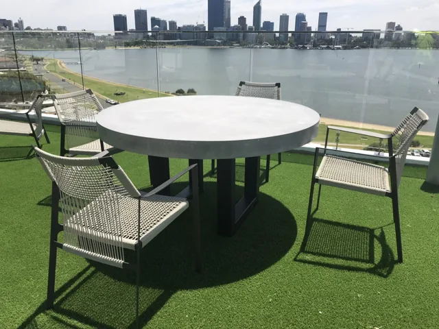 Round balcony table: A round dining top on a dark base in a balcony setting.