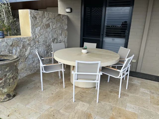 Round pedestal table: A pale round dining table with a cylindrical pedestal base.