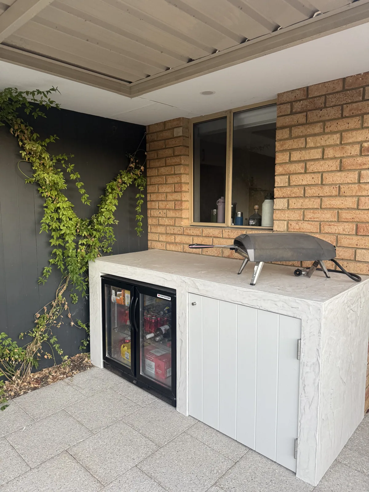 White textured barbecue surround with drinks fridge and white cabinetry